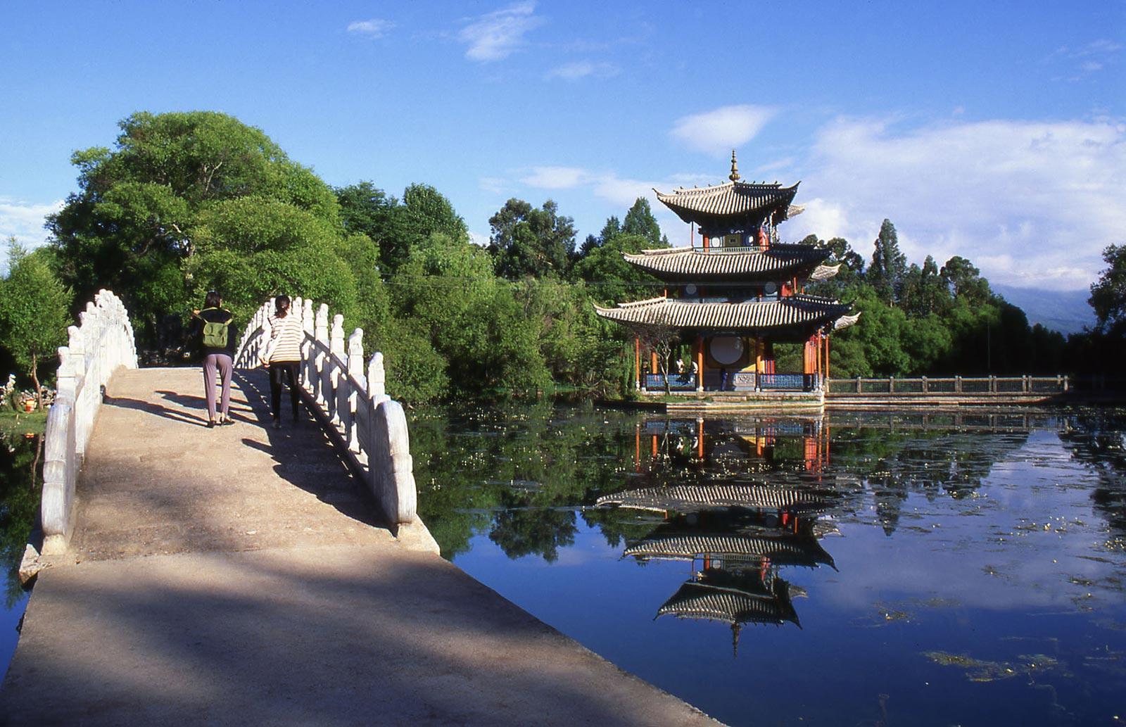 park with bridge over a stream with pagoda in the distance